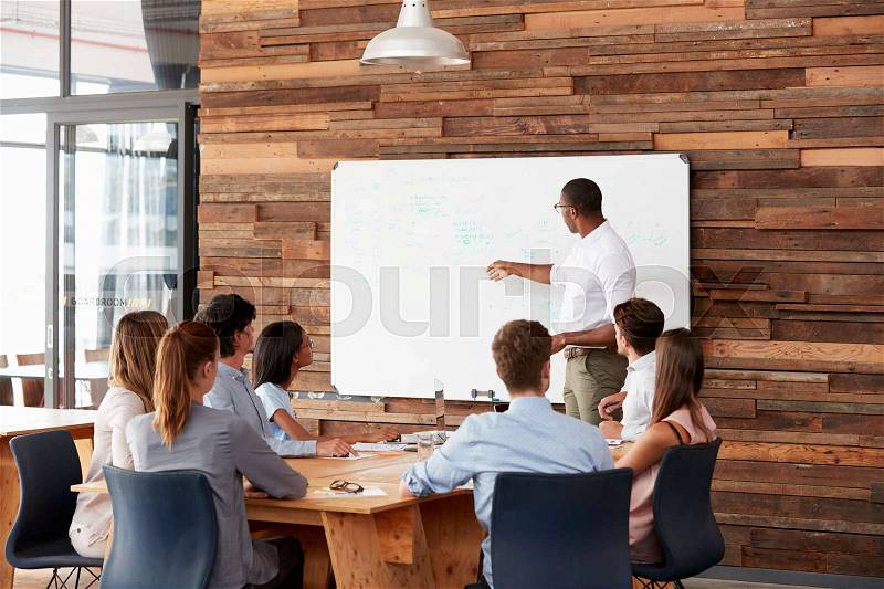 Young black man at whiteboard giving a business presentation, stock photo