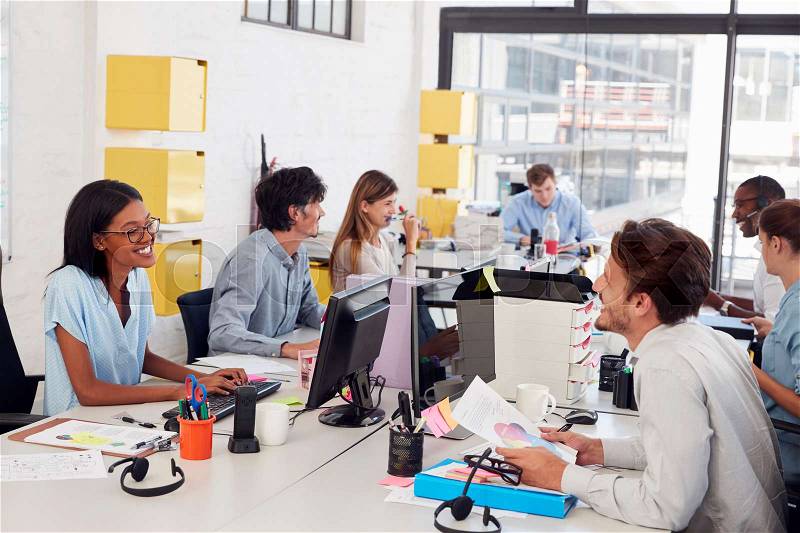Happy young business team working in a busy open plan office, stock photo
