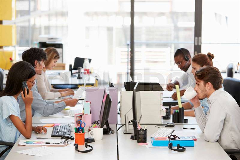 Young colleagues working in a busy open plan office, stock photo