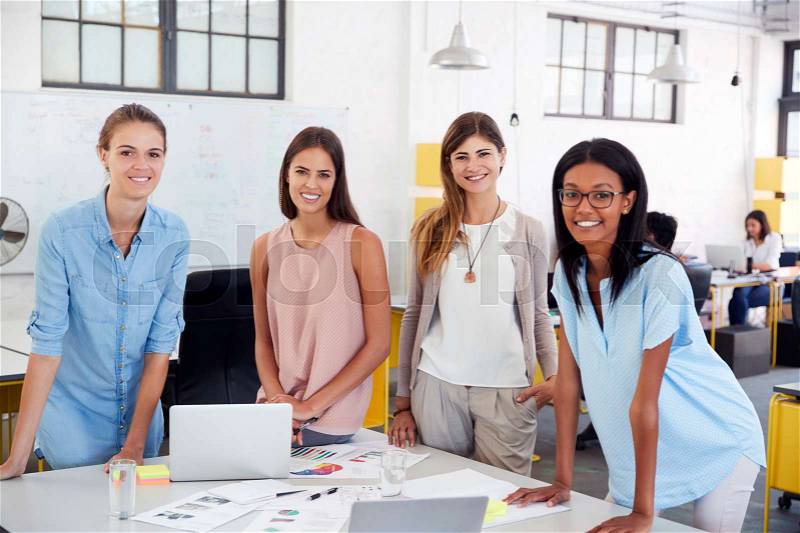 Female business team stand at office desk looking to camera, stock photo