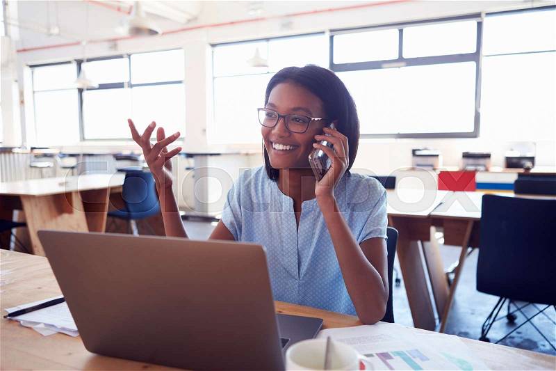 Young black woman on the phone at work in an office , stock photo