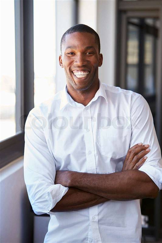 Young black man with arms crossed smiling, vertical portrait, stock photo