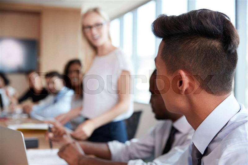 Businesswoman Stands To Address Meeting Around Board Table, stock photo