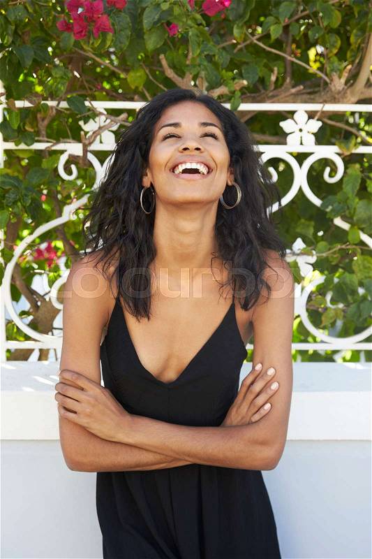 Laughing Latin American woman outdoors with arms crossed, stock photo