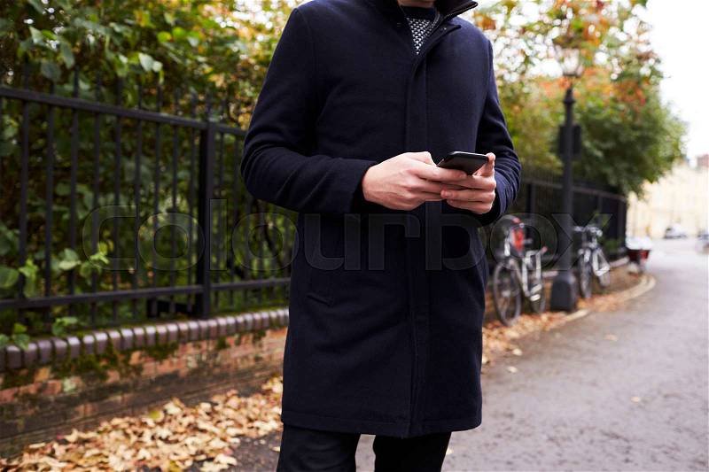 Close Up Of Man Checking Messages On Mobile Phone In Street, stock photo