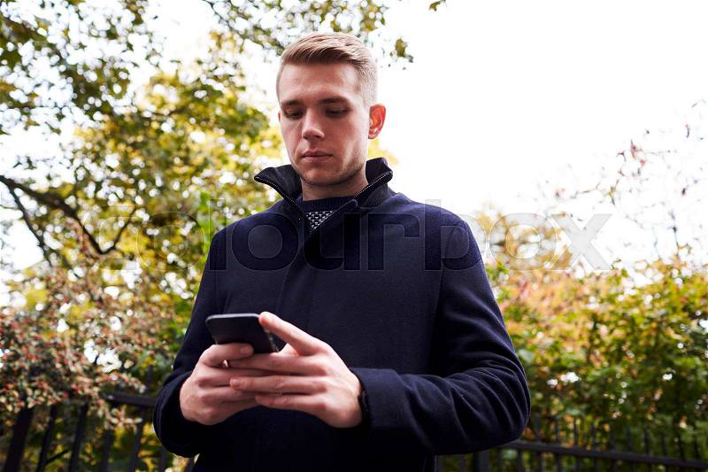 Young Man Checking Messages On Mobile Phone In Oxford Street, stock photo
