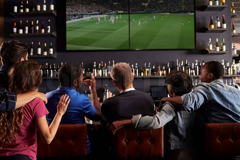 Rear View Of Friends Watching Screen In Bar Together, stock photo