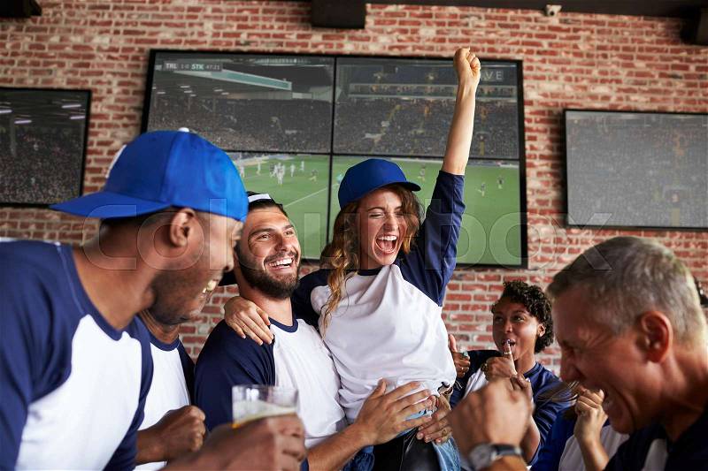 Friends Watching Game In Sports Bar On Screens Celebrating, stock photo