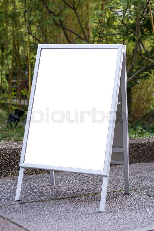 Blank ad space sign infront of trees in a park on the ground, stock photo