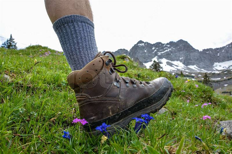 Hiking in the mountains with brown hiking boots and sticks, stock photo