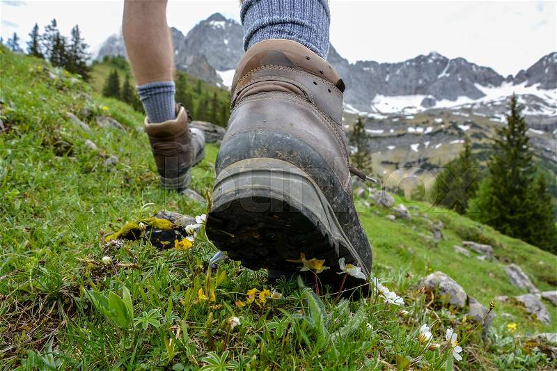 Hiking in the mountains with brown hiking boots and sticks, stock photo