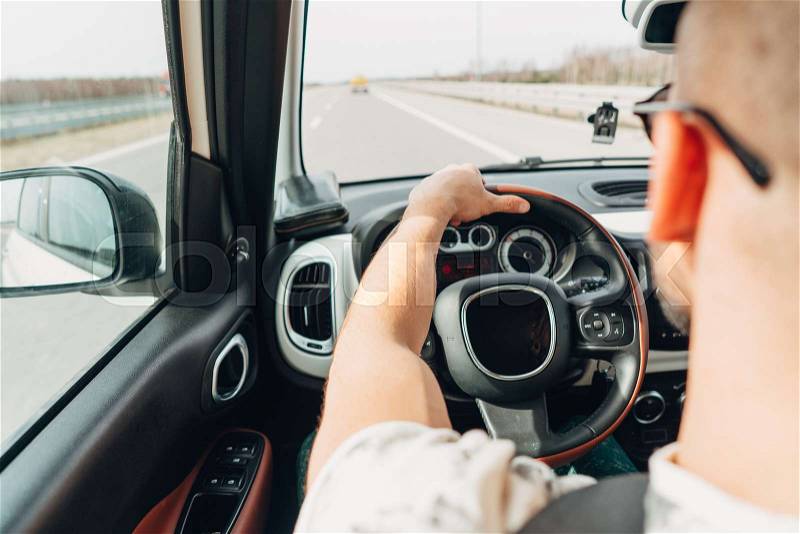 The man behind the wheel of a car traveling on the road, stock photo