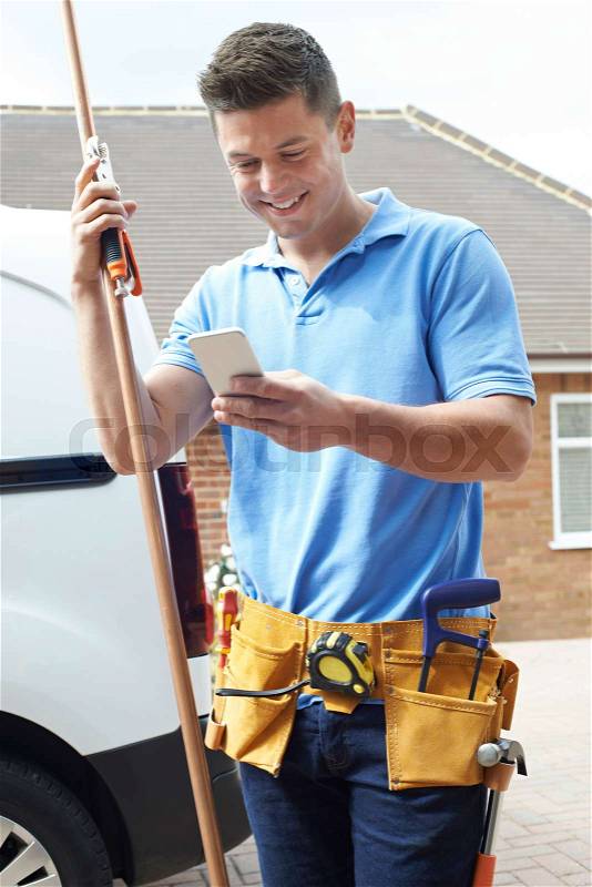 Plumber With Van Texting On Mobile Phone Outside House, stock photo