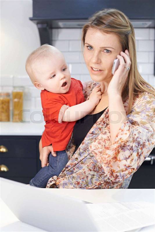 Busy Mother With Baby Coping With Stressful Day At Home, stock photo