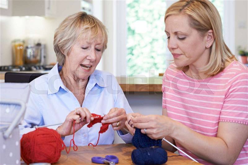 Senior And Mature Female Friends Knitting At Home Together, stock photo