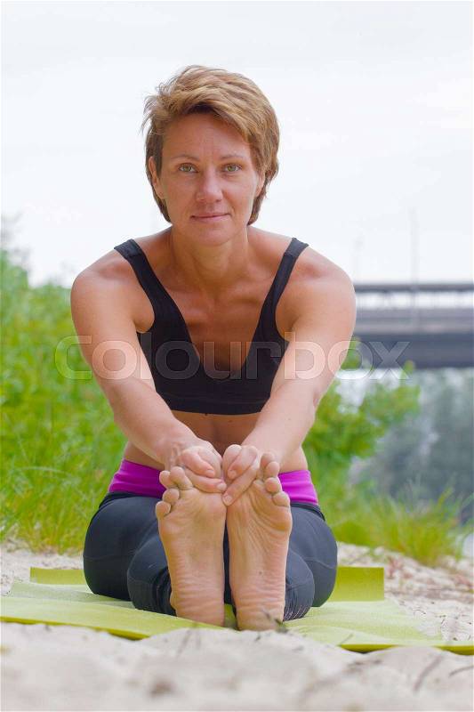 Hatha yoga. Paschimottanasan. Yoga poses, asan. Titl to feet. Concept of healthy life. Practicing yoga, sitting in Head to Knee Forward Bend exercise, Janu Sirsasana pose, wearing sportswear, bra, stock photo