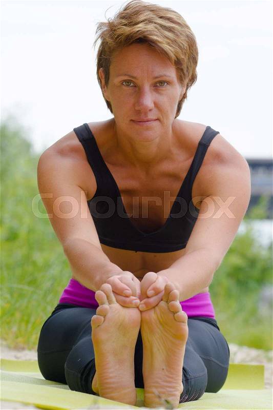 Hatha yoga. Paschimottanasan. Yoga poses, asan. Titl to feet. Concept of healthy life. Practicing yoga, sitting in Head to Knee Forward Bend exercise, Janu Sirsasana pose, wearing sportswear, bra, stock photo