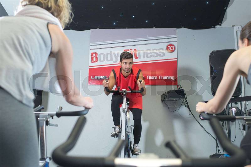 People working out at a stationary bicycle in a gym, stock photo