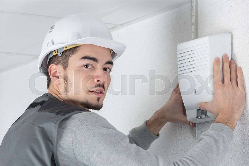 Electrician fitting a thermostat system, stock photo