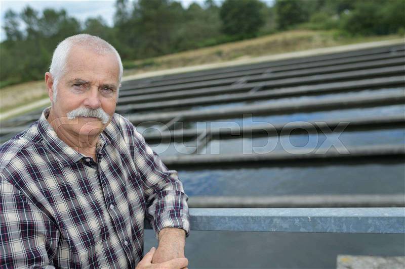 Senior engineer in standing on waste water treatment unit, stock photo