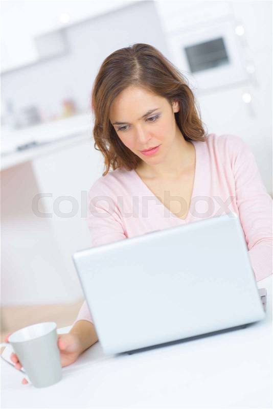 Happy woman using laptop computer and drinking tea, stock photo