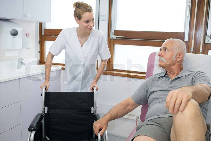Smiling man asking doctor about wheelchairs, stock photo