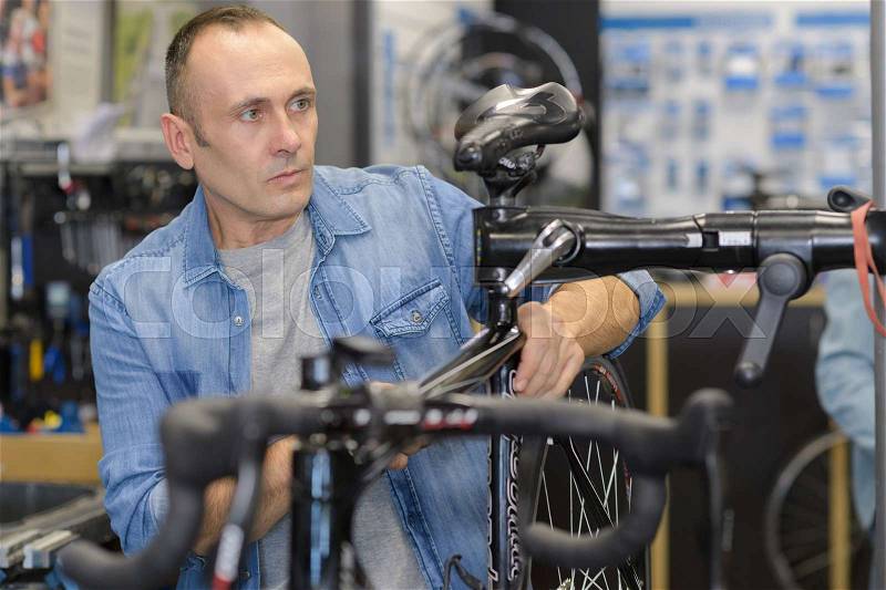 Man getting help from seller in bike store, stock photo