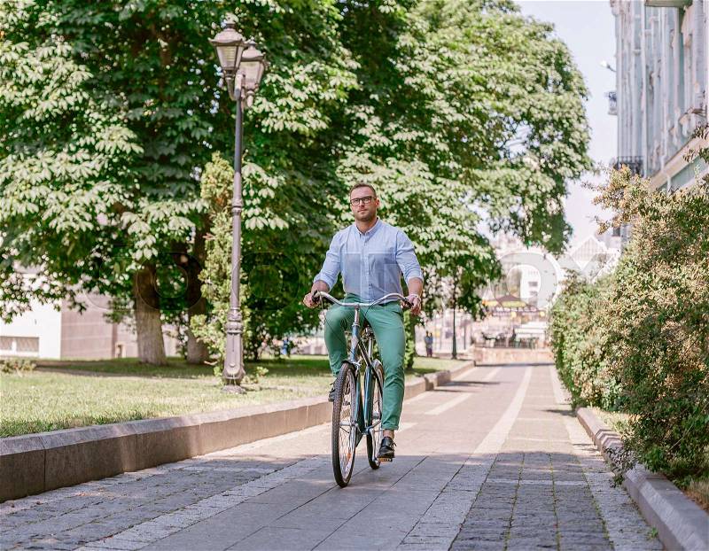 Businessman riding bicycle to work on urban street in morning. Lifestyle, transport, communication and people concept,, stock photo