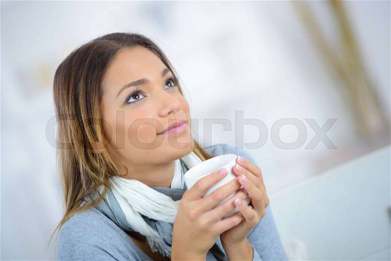 Woman with coffee cup sitting indoors, stock photo