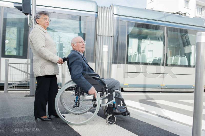 Senior woman pushing man in wheelchair, stock photo