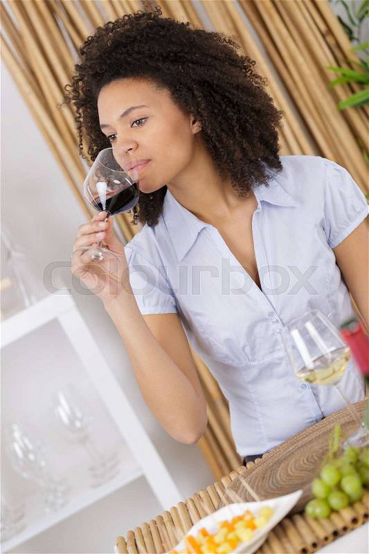 Beautiful woman tasting wine while sitting in restaurant, stock photo