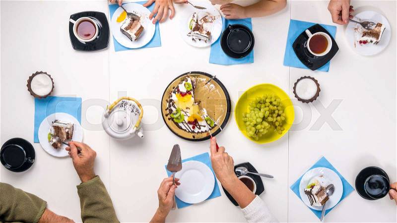 People eating dessert and drinking tea together at white table, top view, stock photo