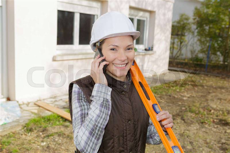 Happy female construction worker on the phone, stock photo