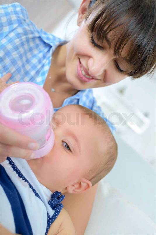 Mother bottle feeding baby, stock photo
