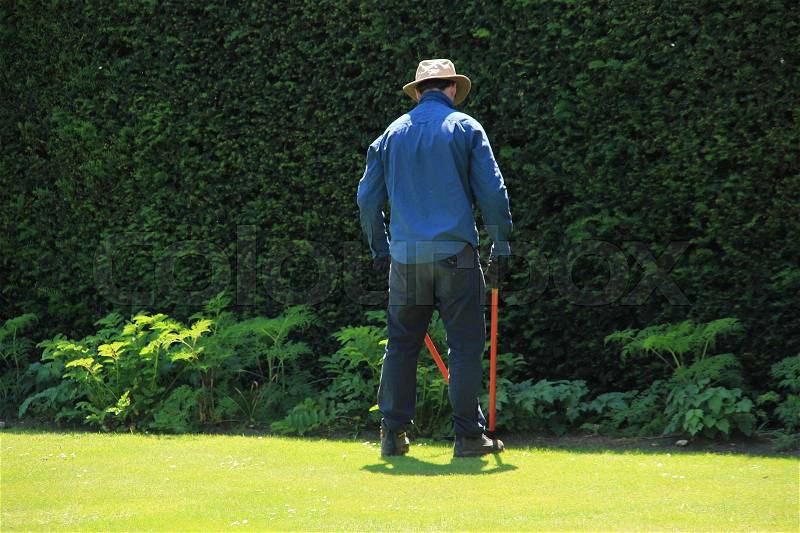 The gardener is cutting the grass in the neighourhood of Leeds Castle in England in the summer, stock photo