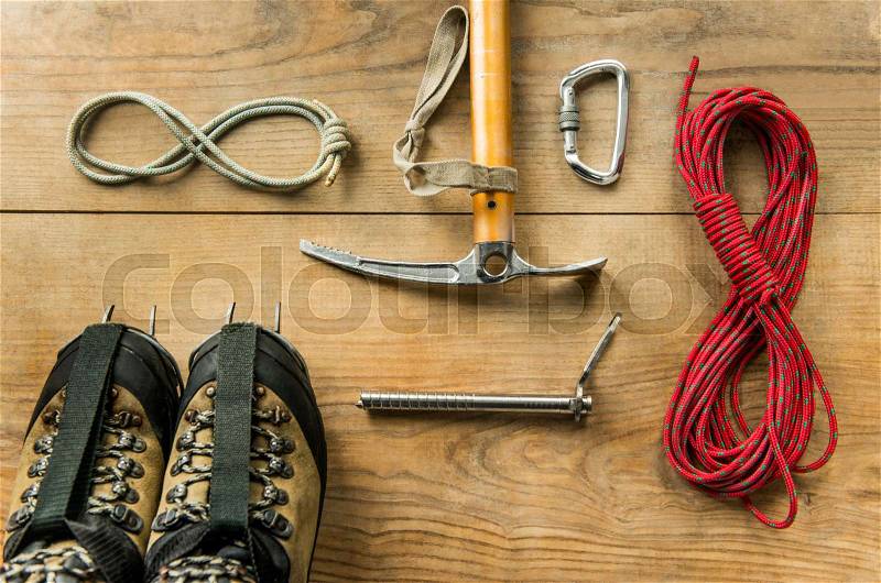 Climbing equipment: rope, trekking shoes, ice tools, ice ax, ice screws, crampons, carbine on wooden background, top view, stock photo