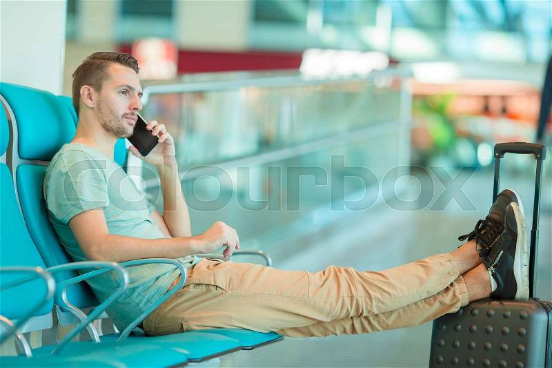 Airline passenger in an airport lounge waiting for flight aircraft. Caucasian woman with smartphone in the waiting room, stock photo