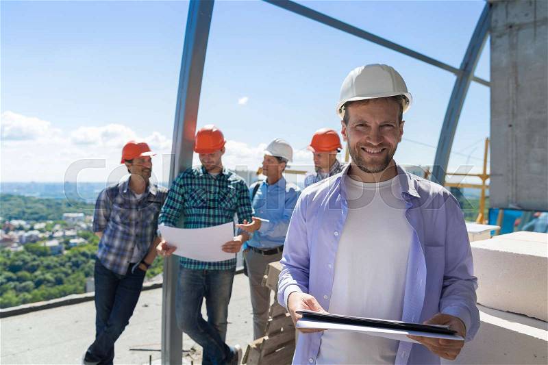 Team Of Builders On Site, Contractor Hold Plan Happy Smiling Over Apprentices Group Discussing Blueprint Engineers Teamwork Concept, stock photo
