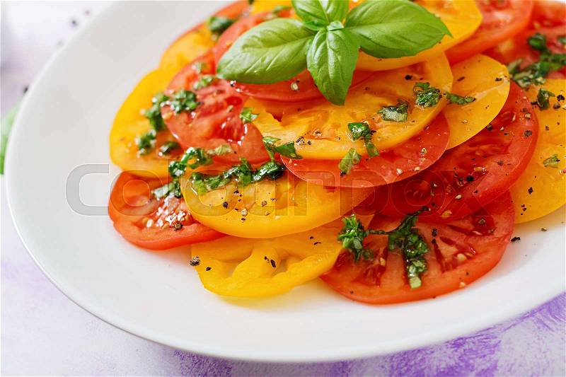Salad of yellow and red tomato with Basil pesto on a light background, stock photo