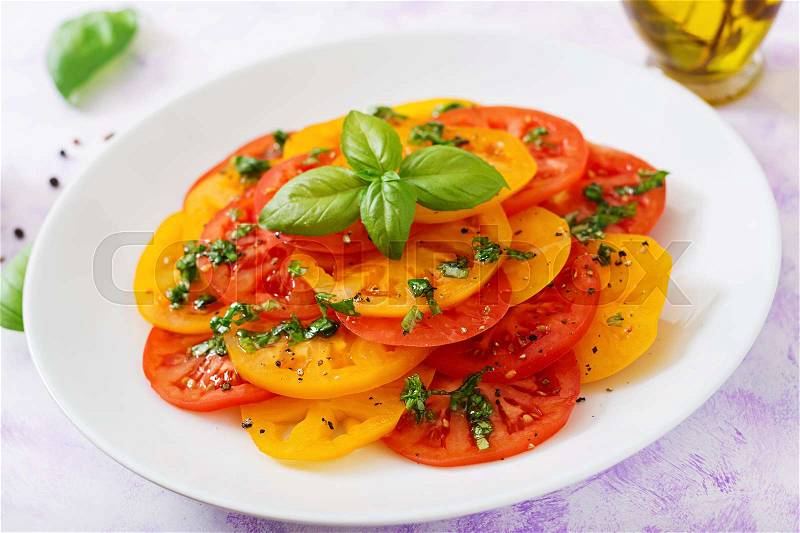 Salad of yellow and red tomato with Basil pesto on a light background, stock photo