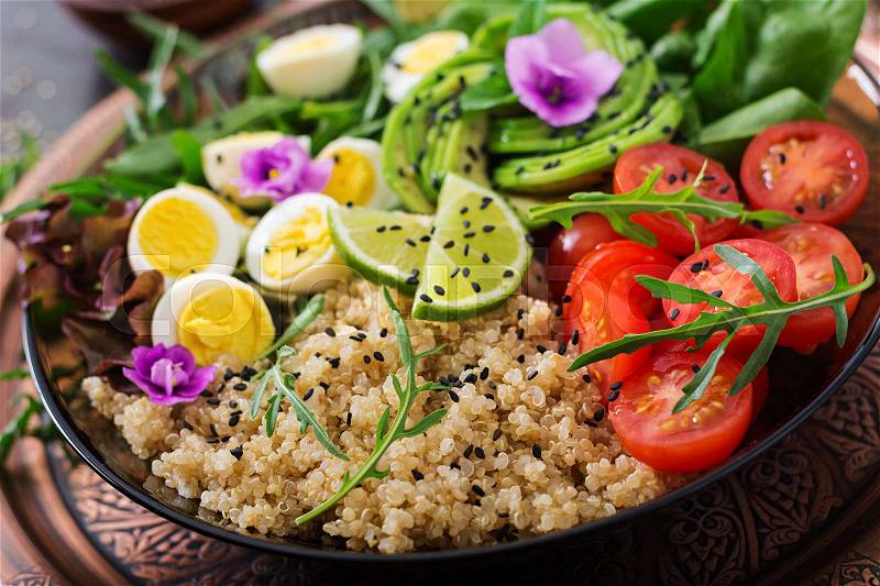 Diet menu. Healthy salad of fresh vegetables - tomatoes, avocado, arugula, egg, spinach and quinoa on a bowl, stock photo