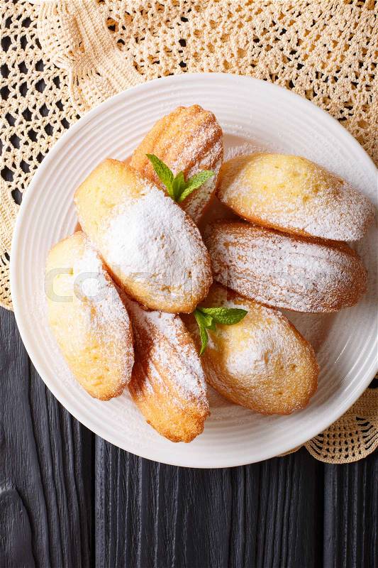 Madeleine biscuits with powdered sugar and mint closeup on a plate on the table. vertical view from above , stock photo