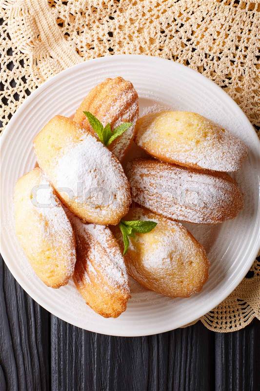 Madeleine\'s biscuit with powdered sugar and mint closeup on a plate on the table. vertical view from above , stock photo