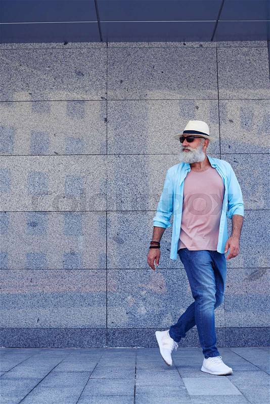 Elderly man turning back, smiling a bit, wearing casual clothing, sunglasses and hat side view, mid shot, stock photo