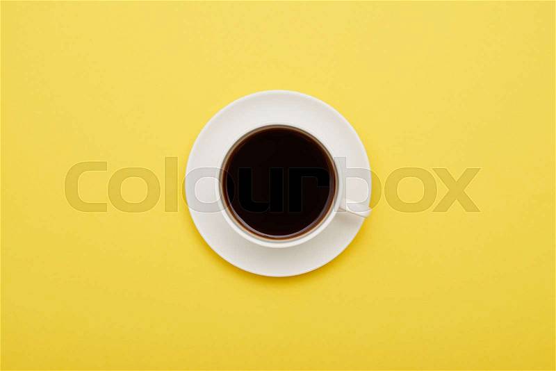 Flat lay of cup of coffee on yellow background with copy space, stock photo