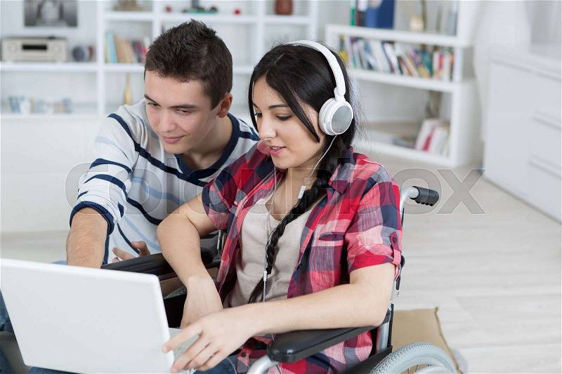 Young people looking at laptop, girl in wheelchair, stock photo