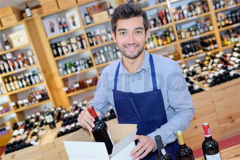 Wine merchant packaging bottles into a box, stock photo