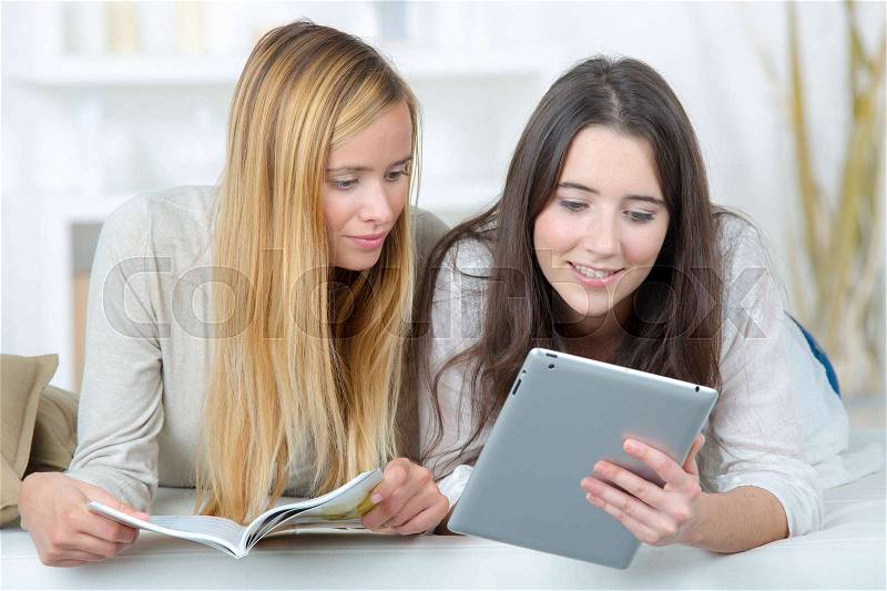 Girls looking at book and tablet screen, stock photo