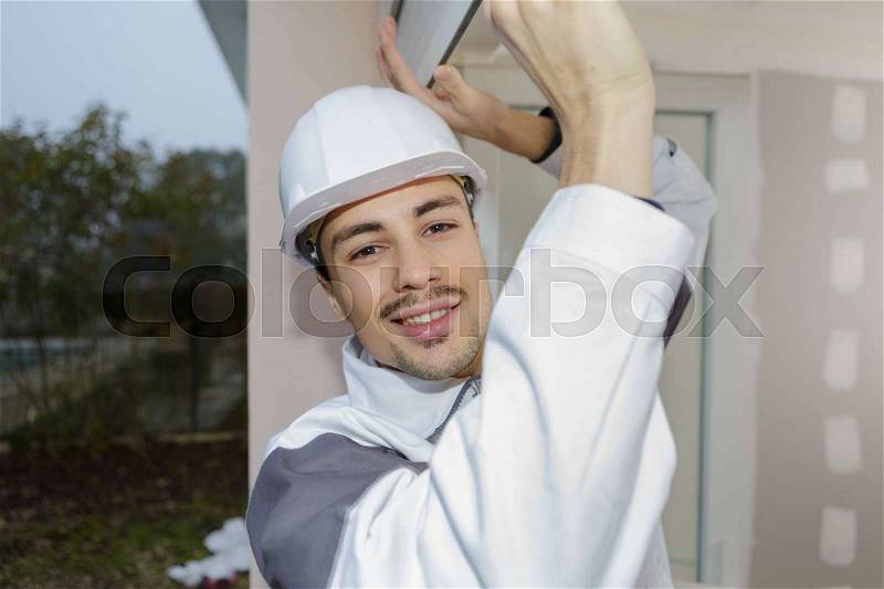 Happy builder sets fittings on the window, stock photo