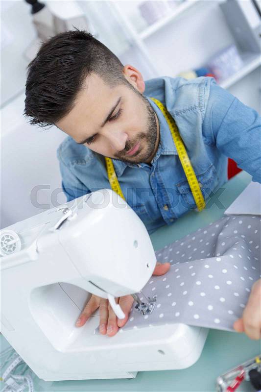 Young man sewing, stock photo